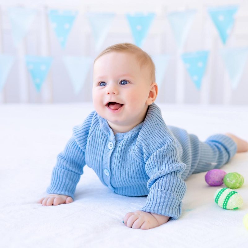 happy-baby-with-colorful-easter-eggs-is-lying-home-bed-white-bed-linen-smiling-easter-greeting-card