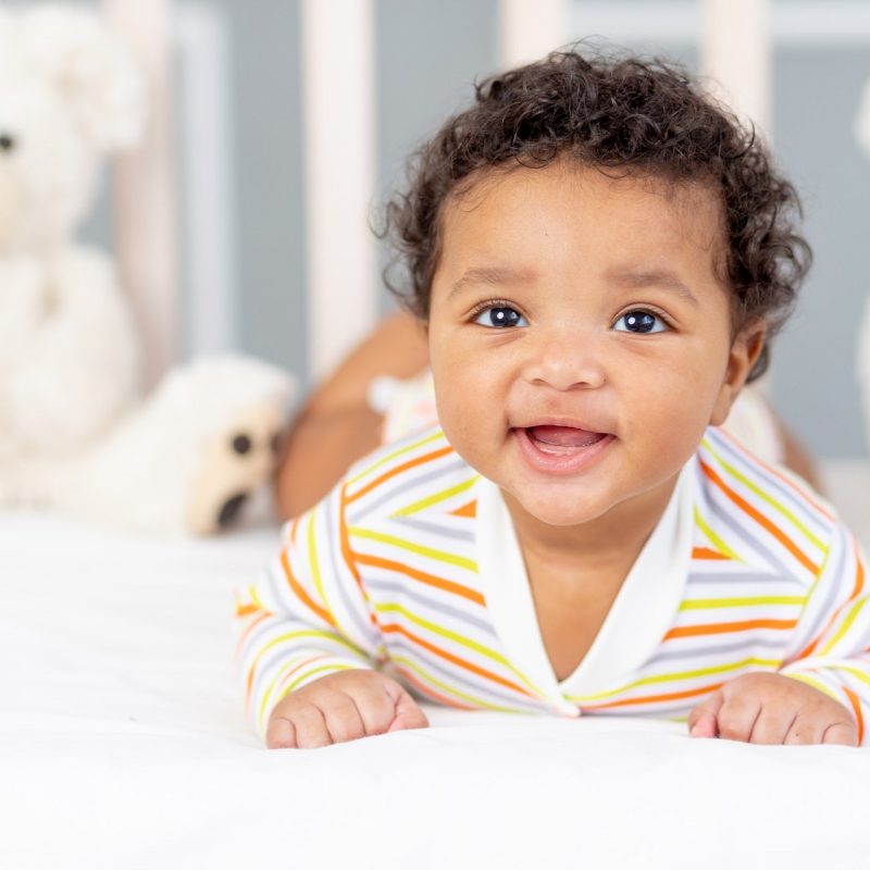 happy-smiling-african-american-little-baby-bed-with-toys